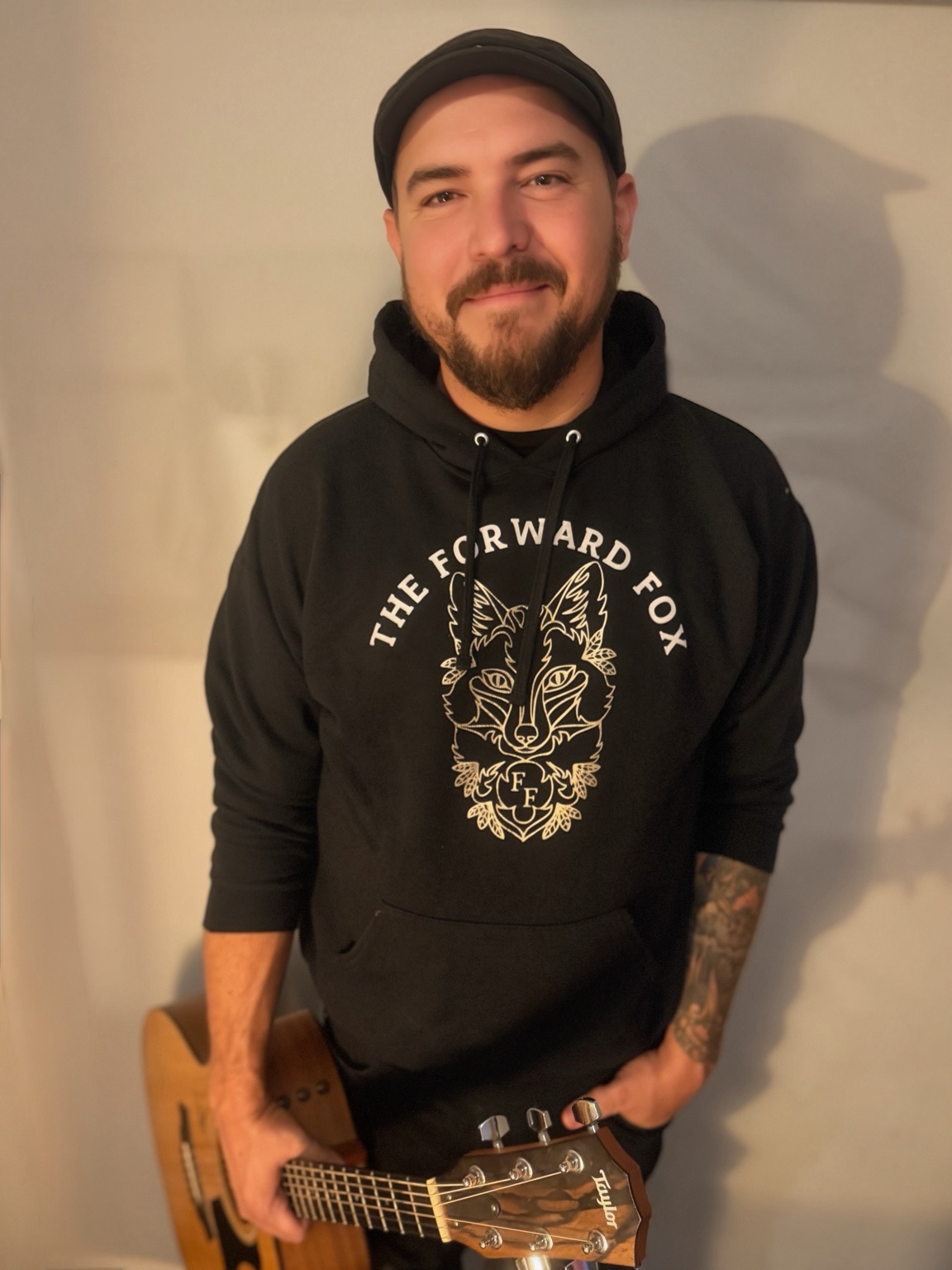 Justin Lamar holding his guitar in a The Forward Fox hoodie
